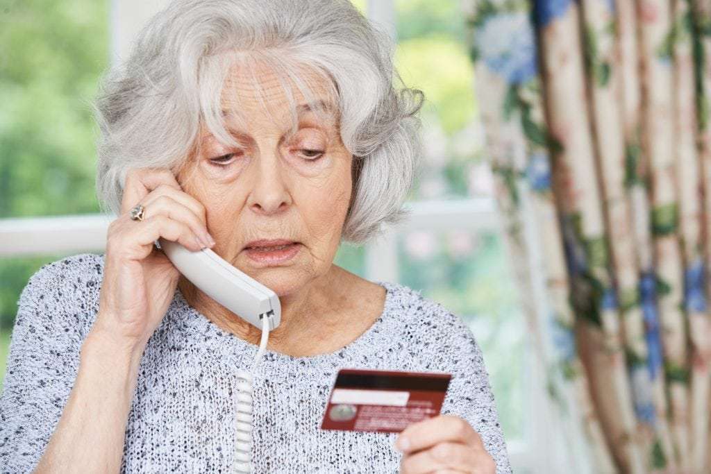 Senior Woman Giving Credit Card Details On The Phone to Timeshare Scam Company