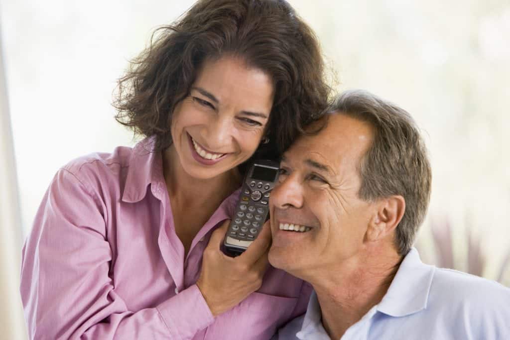 Couple indoors using telephone to talk to timeshare solicitors