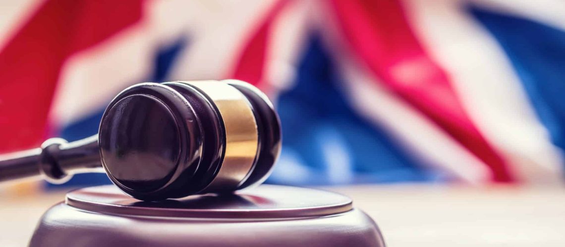 Judges wooden gavel with UK flag in the background. Symbol for jurisdiction.