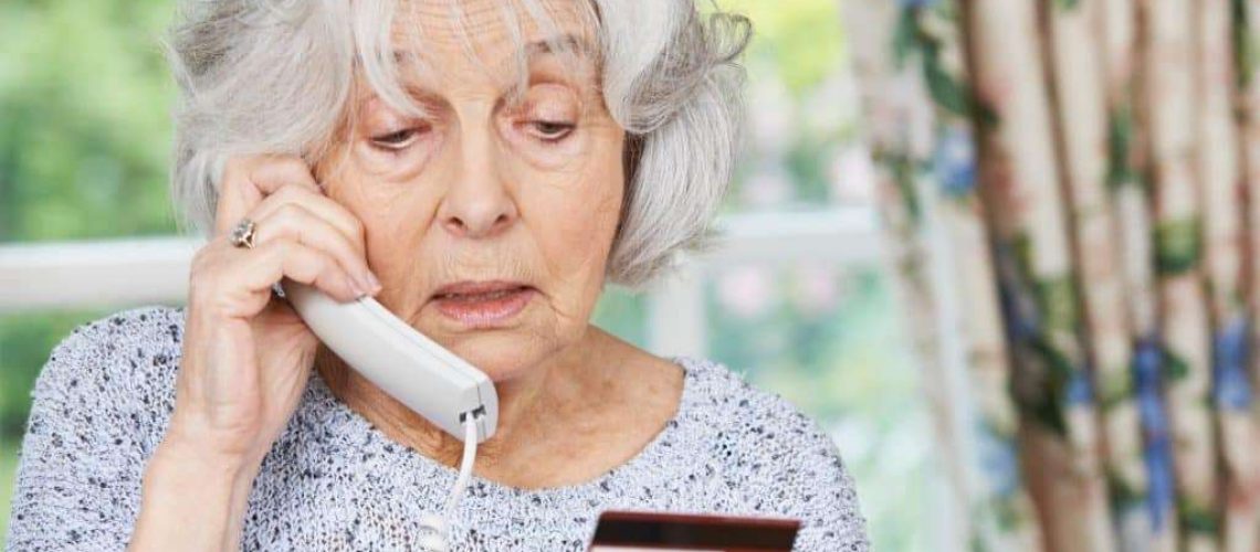 Senior Woman Giving Credit Card Details On The Phone to Timeshare Scam Company