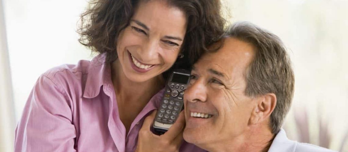 Couple indoors using telephone to talk to timeshare solicitors